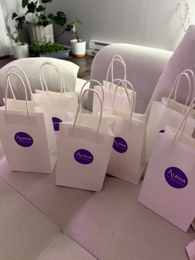 White Alpha Cleaning Agency gift bags with lavender logo stickers prepared for clients